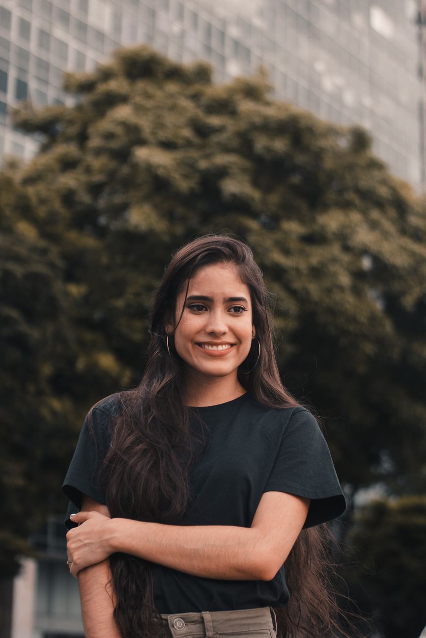 selective focus photo of smiling woman in black t shirt posing while looking away